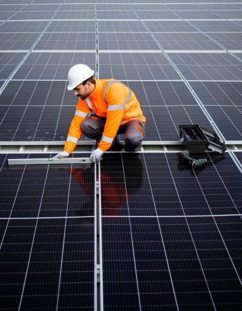 Professional worker checking level and installing solar panel modules on rooftop for sustainable energy.